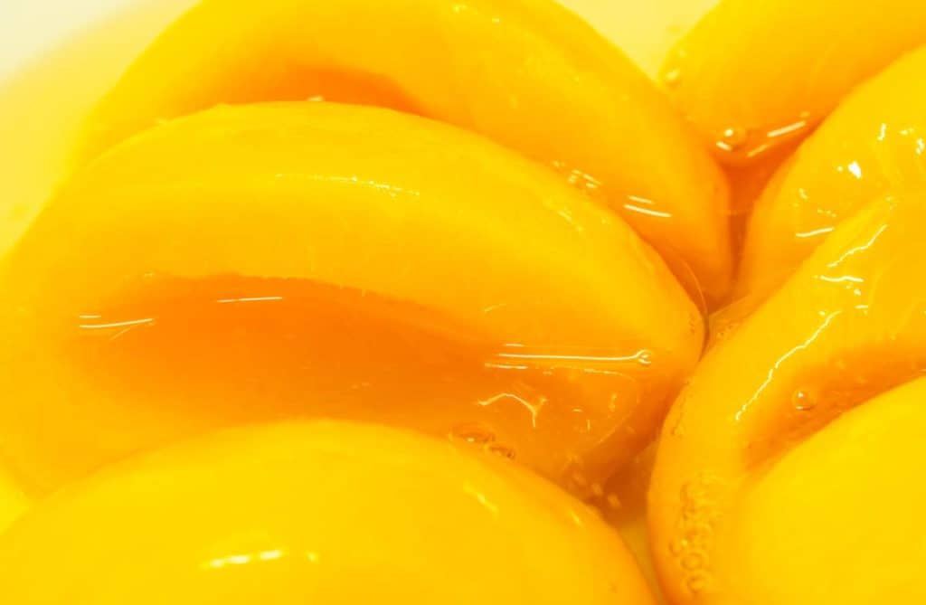 YayImages_HowToMakeHeavySyrupForPeaches_closeup-canned-peach-halves-in-syrup-yellow-fruit